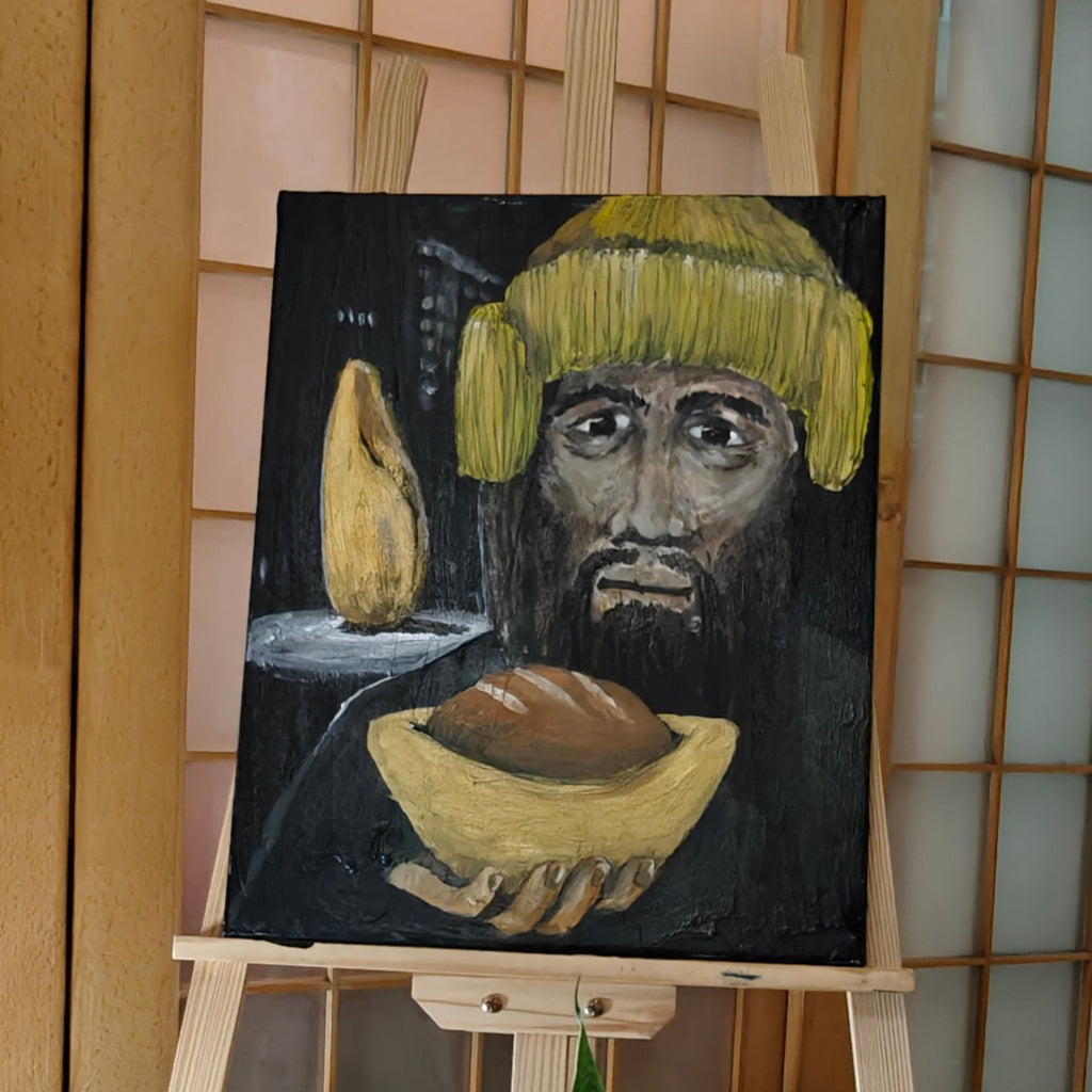 Painting of a face with a yellow hat on an easel in a room with plants and a lantern.